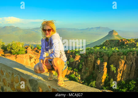 Gerne Touristen sitzen auf den Felsen nach dem Wandern im Tal der Verwüstung in der Nähe von Graaff-Reinet, Südafrika. Abendlicht. Blonde Frau mit Luftaufnahmen, Camdeboo National Park, Karoo, Eastern Cape Stockfoto