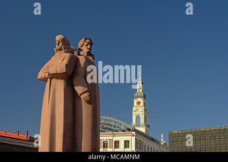 Die Lettischen Gewehrschützen Denkmal in Riga mit Kirche und Busbahnhof Gebäude im Hintergrund an einem sonnigen Tag Stockfoto