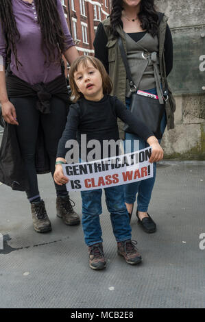 London, Großbritannien. 14. April 2018. Eine junge campainger hält ein kleines Plakat "Gentrifizierung ist Klasse Warr!" zu Beginn der Tour der wohlhabendsten Viertel Londons, vom Land Gerechtigkeit Netzwerk-LED zeigt Landbesitz in Großbritannien ist einer der größten Ungleichheit in der Welt, sowohl in den ländlichen Gegenden und in den Städten. Die Tour begann in Westminster, weitgehend von dem Herzog von Westminster, an relevanten Punkten auf den Grosvenor Estate, Park Lane, im Hyde Park, Grosvenor Crescent und Belgrave Square für Informationen und Reden zu stoppen, endend am 93 Hektar des Cadogan Immobilien, die wohlhabendste Teil der Kensingt Stockfoto