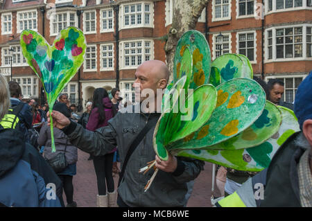 London, Großbritannien. 14 Apr, 2018. Ein Mann Hände Grenfell Herzen wie Menschen, darunter viele, die Familie und Freunde an Grenfell verloren sammeln an einer leisen Spaziergang Kennzeichnung 10 Monate seit der Katastrophe zu nehmen. Sie trafen sich an der Kensington Town Hall zu betonen, dass Sie halten Kensington und Chelsea Rat für die Tragödie und nicht wirksam mit den Nachwirkungen zu tun verantwortlich ist, mit vielen Überlebenden noch nicht richtig rehoused. Credit: Peter Marschall/Alamy leben Nachrichten Stockfoto