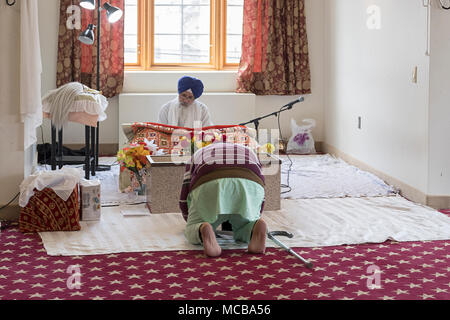 Mit einem Mann, einem Sikh Priester, ein Granthi, lesen Sri Guru Granth Sahib, dem heiligen Buch der Sikhs. In Richmond Hill in Queens, New York. Stockfoto