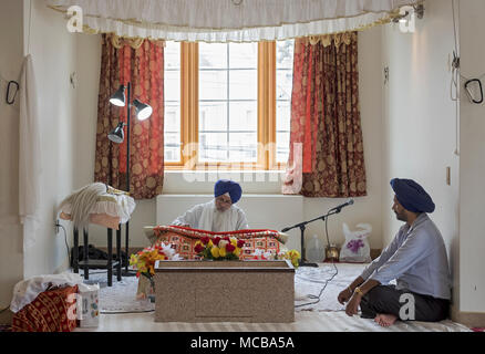 Mit einem Zuschauer, ein Sikh Priester, ein Granthi, lesen Sri Guru Granth Sahib, dem heiligen Buch der Sikhs. In Richmond Hill in Queens, New York. Stockfoto