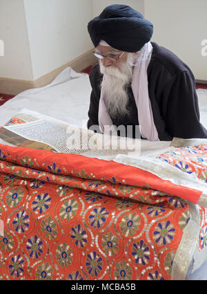 Sikh Priester, ein Granthi, lesen Sri Guru Granth Sahib, dem heiligen Buch der Sikhs. In Richmond Hill in Queens, New York. Stockfoto