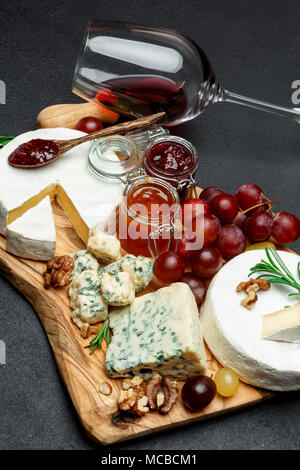 Verschiedene Arten von Käse, Marmelade und Wein auf Holz Schneidebrett Stockfoto