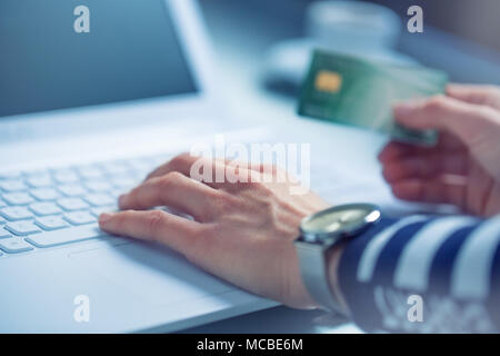 Frau Hände Tippen auf der Tastatur des Laptops holding Kreditkarte, close-up der On-line-Einkaufen. Stockfoto