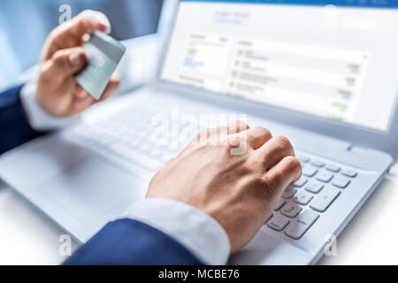 Man Hände Tippen auf der Tastatur des Laptops holding Kreditkarte, close-up der On-line-Einkaufen. Stockfoto