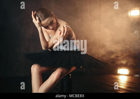 Ballerina sitzend auf schwarze Sitzbank im Theater Stockfoto