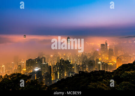 Misty Stadt Blick vom Peak bei Dämmerung - Victoria Harbour in Hong Kong Stockfoto