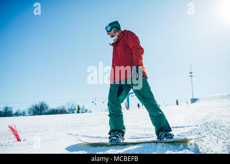 Snowboarder in Gläsern wirft mit Board in den Händen Stockfoto