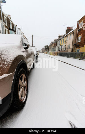 England, Ramsgate. Verschneite Straße am frühen Morgen nach dem Schneefall, mit parkenden Autos auf der Seite im Vordergrund, close-up. Stockfoto