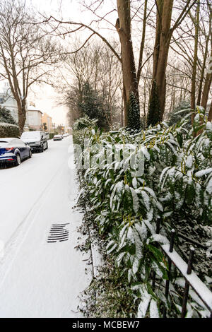 England, Ramsgate. Verschneite Straße am frühen Morgen nach snowfal, mit Schnee Absicherung auf der einen Seite abgedeckt, Autos auf der anderen Seite geparkt. Stockfoto