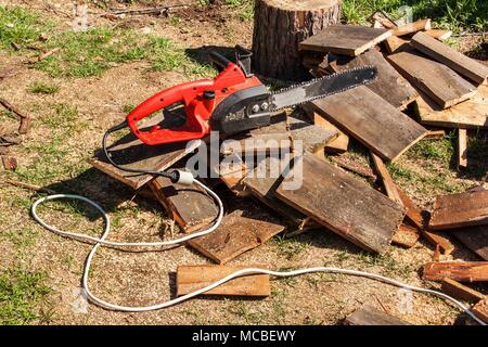 Elektrische Sägen und Kettensäge. Elektrische Säge Kette auf dem Hintergrund von Schnittholz. Das Konzept der Verarbeitung von Holz Brennstoff zu produzieren Stockfoto