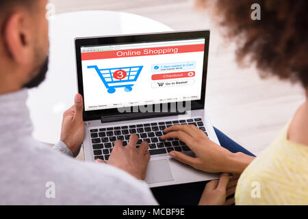 Paar tun Online Shopping auf Laptop mit Karre auf dem Bildschirm Stockfoto