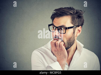 In dem Bestreben, junge Mann seine Fingernägel beißen auf die Seite schauen Beschäftigt Stockfoto