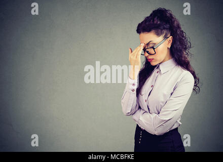 Schöne Brünette in elegantem Outfit und Gläser müde, Kopfschmerzen und rieb Stirn mit geschlossenen Augen. Stockfoto