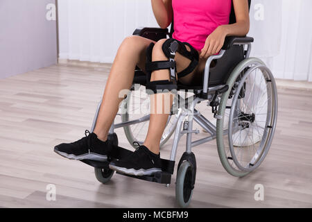 Weibliche Patienten mit Knie Klammern Sitzen auf Rollstuhl Stockfoto