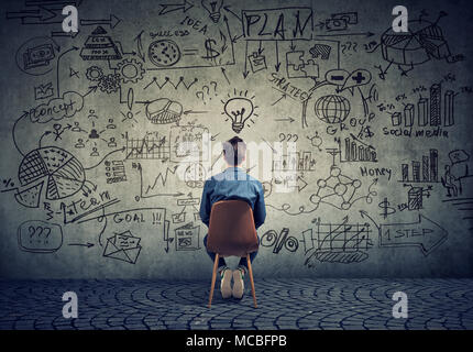 Rückansicht der Freiberufler Mann sitzt vor der Wand mit Strategie und Erstellen eines Plans. Stockfoto