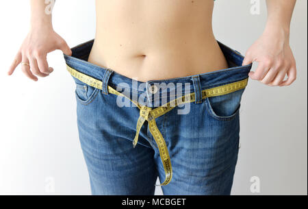 Gewicht-verlust-Konzept. Frau zeigt Ihr Gewicht Verlust durch das Tragen einer alten Jeans. Gesunder Lebensstil, Diät Konzept mit übergroßen Jeans. Stockfoto