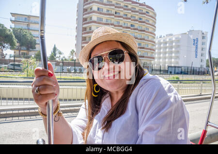 Eine Dame trägt einen Sonnenhut und Sonnenbrille posiert für ein Foto. Stockfoto
