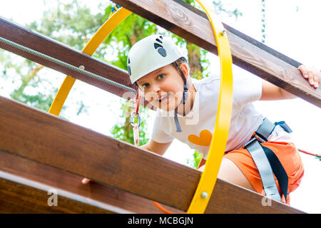 Junge Mädchen im Kabelbaum klettern und versuchen, in einem Adventure Park. Stockfoto