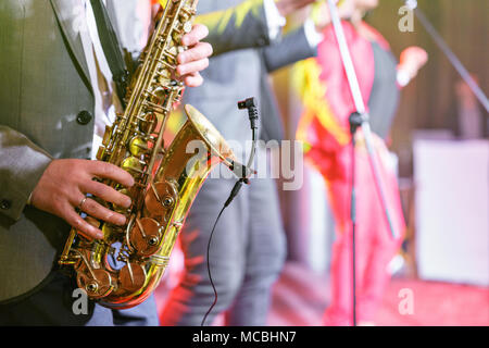 Ein junger Mann im Anzug spielen auf Saxophon. Elegante saxophonist spielt Jazz. close-up Musikinstrument, Sax im Vordergrund. Stockfoto