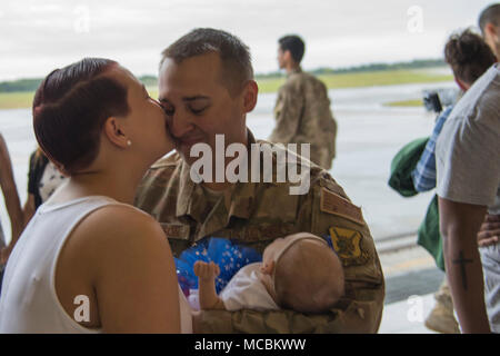 Airman 1st Class Aaron Thompson, 822Nd Base Defense Squadron fire Team Mitglied, erhält einen Kuss von seiner Frau, Jess, und hält seine Tochter, Luna, während eine Umschichtung Zeremonie März 30, 2018, bei Moody Air Force Base, Ga die 822Nd BDS kehrte nach mehreren Monaten bereitgestellt und erwerben zahlreiche Befehl, Flügel und individuelle Auszeichnungen. Stockfoto