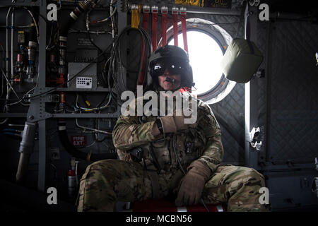 Ein flugingenieur mit US-Armee Task Force Schläger, sitzt an Bord eines CH-47 Chinook F während einer Ausbildung Flug am Flughafen Bagram, Afghanistan, 26. März 2018. Die Armee der Besatzungen und Air Force Schutzengel Teams durchgeführt, um die Übung Teamwork und Verfahren zu bauen, wie Sie gemeinsame Personal Recovery Funktionen bieten, die in der Lieferung von entscheidender Airpower für US Central Command. Stockfoto