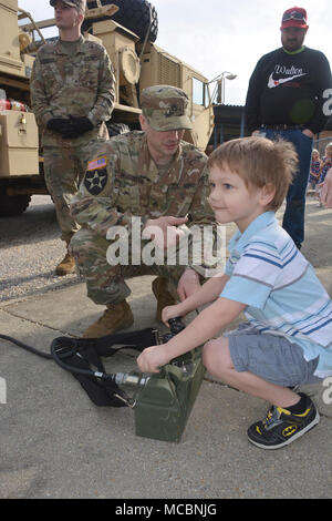 Damion Dickens, ein pre-kindergarten Student an der Walton Elementare, drückt Hebel ein Kran auf eine Armee schwere Erweiterte Mobilität Tactical Truck mit Staff Sgt. Kyle McGovern, ein radfahrzeug Mechaniker, 111 Quartermaster Unternehmen, während der Schule Wissenschaft, Technologie, Ingenieurwesen, Kunst und Mathe tag März 29. Soldaten aus Charlie Company, 16 Ordnance Battalion - Staff Sgt. Yolanda Walker, platoon Sergeant, und 1 Sgt. Mindy Shearin, Firma first Sergeant - bis die statische Darstellung von der 111 QM-Co für ihre Adopt-a-School Dampf die Schüler wie die HEMTT IST INV angezeigt werden Stockfoto