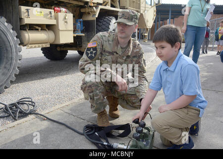 Jackson Wroble, ein Kindergarten Student an der Walton Elementare, drückt Hebel ein Kran auf eine Armee schwere Erweiterte Mobilität Tactical Truck mit Staff Sgt. Kyle McGovern, ein radfahrzeug Mechaniker, 111 Quartermaster Unternehmen, während der Schule Wissenschaft, Technologie, Ingenieurwesen, Kunst und Mathe tag März 29. Soldaten aus Charlie Company, 16 Ordnance Battalion - Staff Sgt. Yolanda Walker, platoon Sergeant, und 1 Sgt. Mindy Shearin, Firma first Sergeant - Die statische Darstellung von der 111 QM-Co für ihre Adopt-a-School DAMPF Programm zeigen Sie den Kursteilnehmern, wie die HEMTT IST Stockfoto