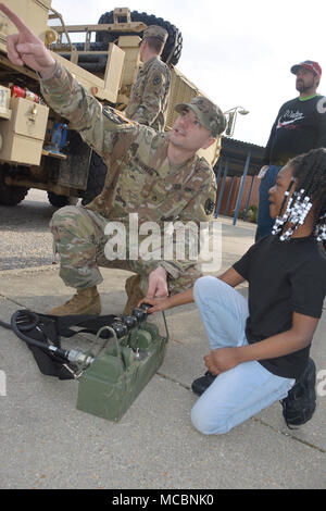 Nevaeh Patrick, ein pre-kindergarten Student an der Walton Elementare, drückt Hebel ein Kran auf eine Armee schwere Erweiterte Mobilität Tactical Truck mit Staff Sgt. Kyle McGovern, ein radfahrzeug Mechaniker, 111 Quartermaster Unternehmen, während der Schule Wissenschaft, Technologie, Ingenieurwesen, Kunst und Mathe tag März 29. Soldaten aus Charlie Company, 16 Ordnance Battalion - Staff Sgt. Yolanda Walker, platoon Sergeant, und 1 Sgt. Mindy Shearin, Firma first Sergeant - bis die statische Darstellung von der 111 QM-Co für ihre Adopt-a-School Dampf die Schüler wie die HEMTT IST INV angezeigt werden Stockfoto