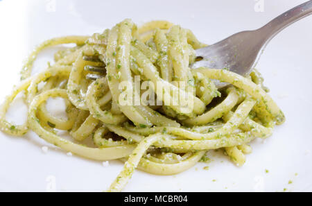 Italienische Küche Spaghetti. Spaghetti mit hausgemachtem Pesto und Basilikum Blätter auf dem Tisch mit Sonnenlicht Hintergrund, Spaghetti mit grüner Soße in der Stockfoto