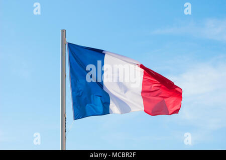 Französische Flagge in einem lebhaften Brise flattern vor einem strahlend blauen Himmel im Sommer Hintergrund. Stockfoto