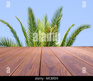 Leere Holztisch mit grünen Palmen im Sommer blauer Himmel, kann für die Anzeige montage Konzept verwenden. Stockfoto