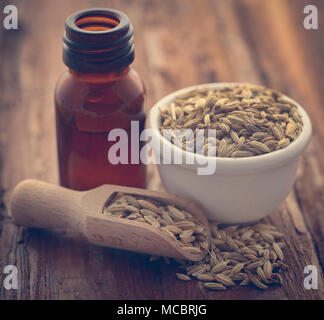 Fenchel Samen mit ätherischen Öl in eine Flasche in Holz- Oberfläche Stockfoto