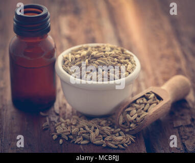 Fenchel Samen mit ätherischen Öl in eine Flasche in Holz- Oberfläche Stockfoto