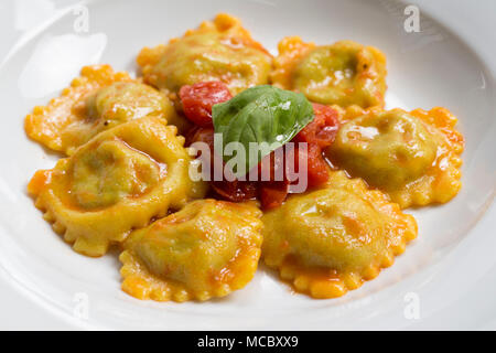 Der frontalen Schuss ein typisch italienisches Gericht, ein Teller Ravioli mit Gemüse und Tomatensoße und Basilikum auf oben gefüllt Stockfoto