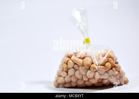 Raw Arachis Hypogaea, Erdnuss oder Erdnüsse in einer Tasche auf dem isolierten weißen Hintergrund. Stockfoto