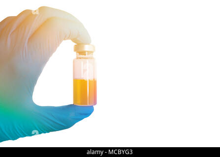 Die Hand in der medizinischen Handschuh hält ein Reagenzglas mit einer Flüssigkeit der Farbe Gelb. Impfstoffe, Gifte. Stockfoto