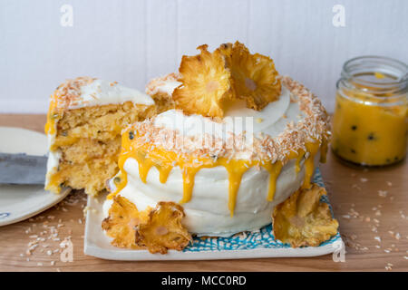 In Scheiben geschnittene Ananas und Kokosnuss Layer Cake, serviert mit Passionsfrucht Soße auf handgefertigte Keramik Platten. Stockfoto