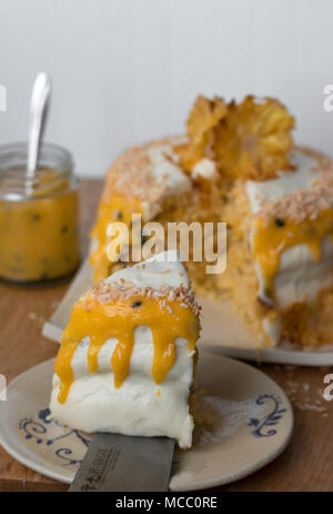 Eine Scheibe Ananas Kokos Layer Cake mit Passionsfrucht Sauce. Auf handgefertigten Teller serviert. Stockfoto