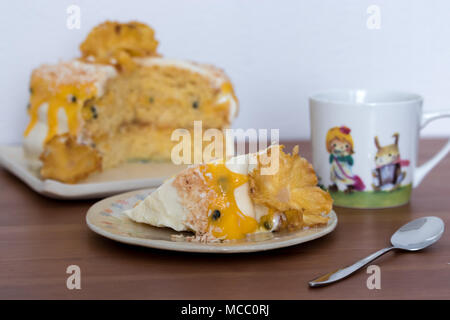 Tee am Nachmittag. Eine Scheibe Ananas und Kokosnuss Layer Cake mit Passionsfrucht Quark. Auf handgefertigten Teller serviert. Stockfoto