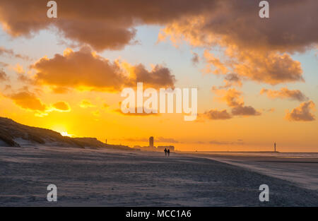 Silhouetten von ein Paar einen romantischen Spaziergang am Strand von Oostende zwischen Dünen und Nordsee bei Sonnenuntergang mit der Skyline der Stadt, Belgien Stockfoto