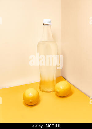 Limonade in der Flasche Glasfläschchen mit Limonade und zwei ganze Zitronen in der Nähe stehen gegen Licht wand Trendy Foto mockup mit Kopie spac Stockfoto