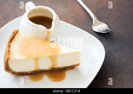 Käsekuchen mit Karamellsauce auf weiße Platte, Detailansicht, selektiver Fokus Stockfoto