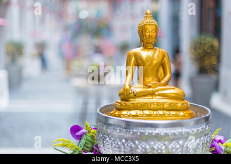 Kleine Goldene gelbe Buddha Statue Einstellung auf einem Tisch, an einem öffentlichen Ort für Menschen, die auf Beute Achtung Während der Song Kran Wasser Festival in Chiang Mai, Stockfoto