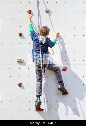 Junge Weise oben auf einem weißen Kletterwand Stockfoto