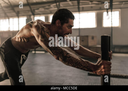 Haltbare junge Mann drücken Schlitten in Cross Training Gym. Muskulöse Mann tun, intensiven körperlichen Training in Health Club. Stockfoto