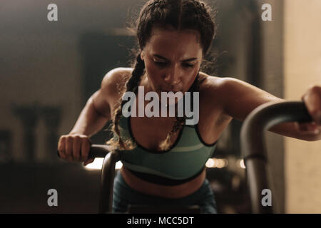 Frau, die intensives Training auf dem Fitnessrad macht. Fitnesstraining weiblich mit Air Bike für Cardio-Workout im Fitnessstudio. Stockfoto