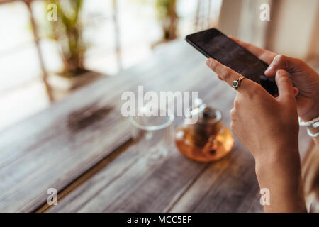 Nahaufnahme einer Frau Erfassen von Fotos einer Teekanne aus Glas und eine leere mit einem Handy für ihr Essen blog Glas. Essen blogger ein Foto für Ihre Stockfoto