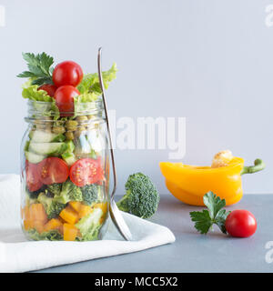 Gemüse gesund Hausgemachte detox Bunter Salat im Marmeladenglas mit Tomaten, Salat, gelb Papper auf blauem Hintergrund. Kopieren Sie Platz. Für das Mittagessen. Stockfoto